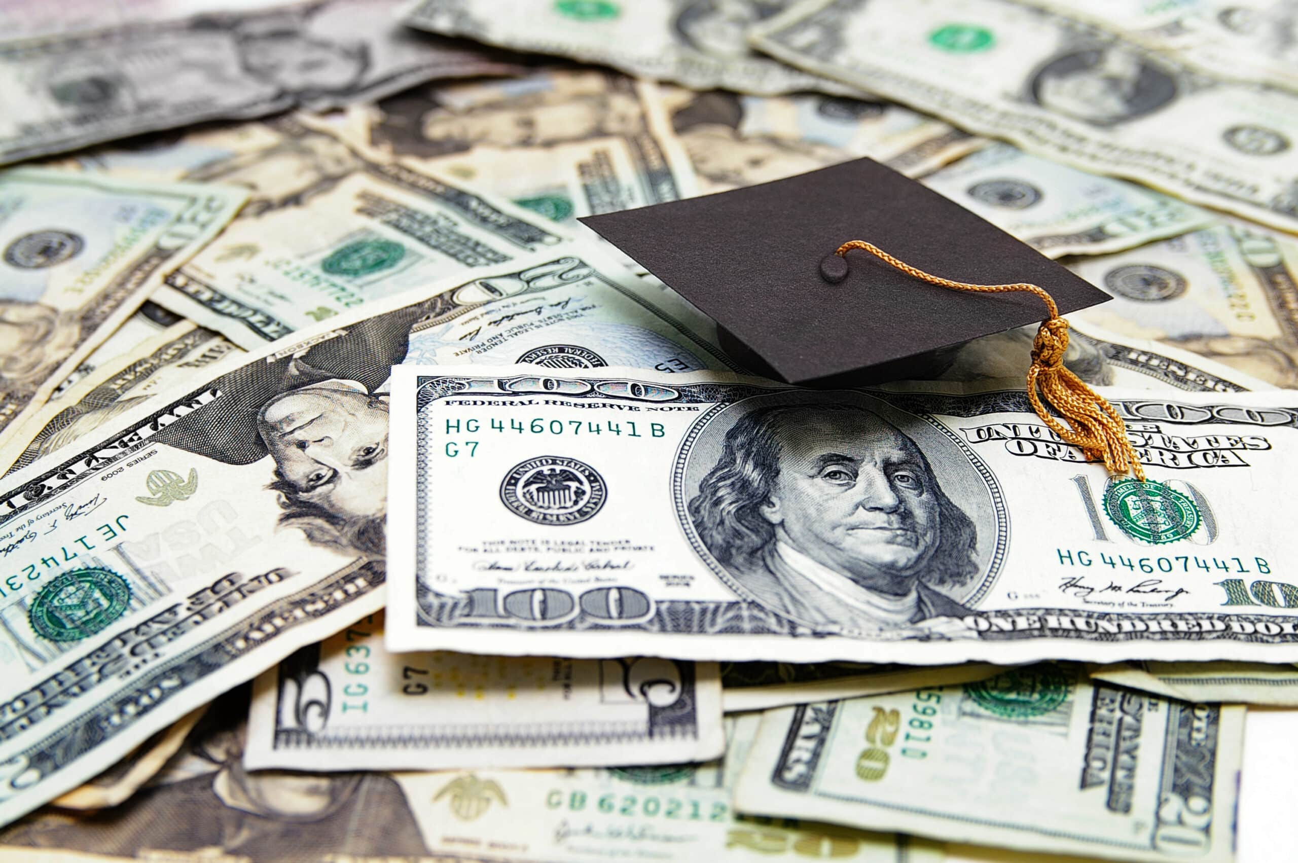academic cap on top of dollars bills to represent financial support for education